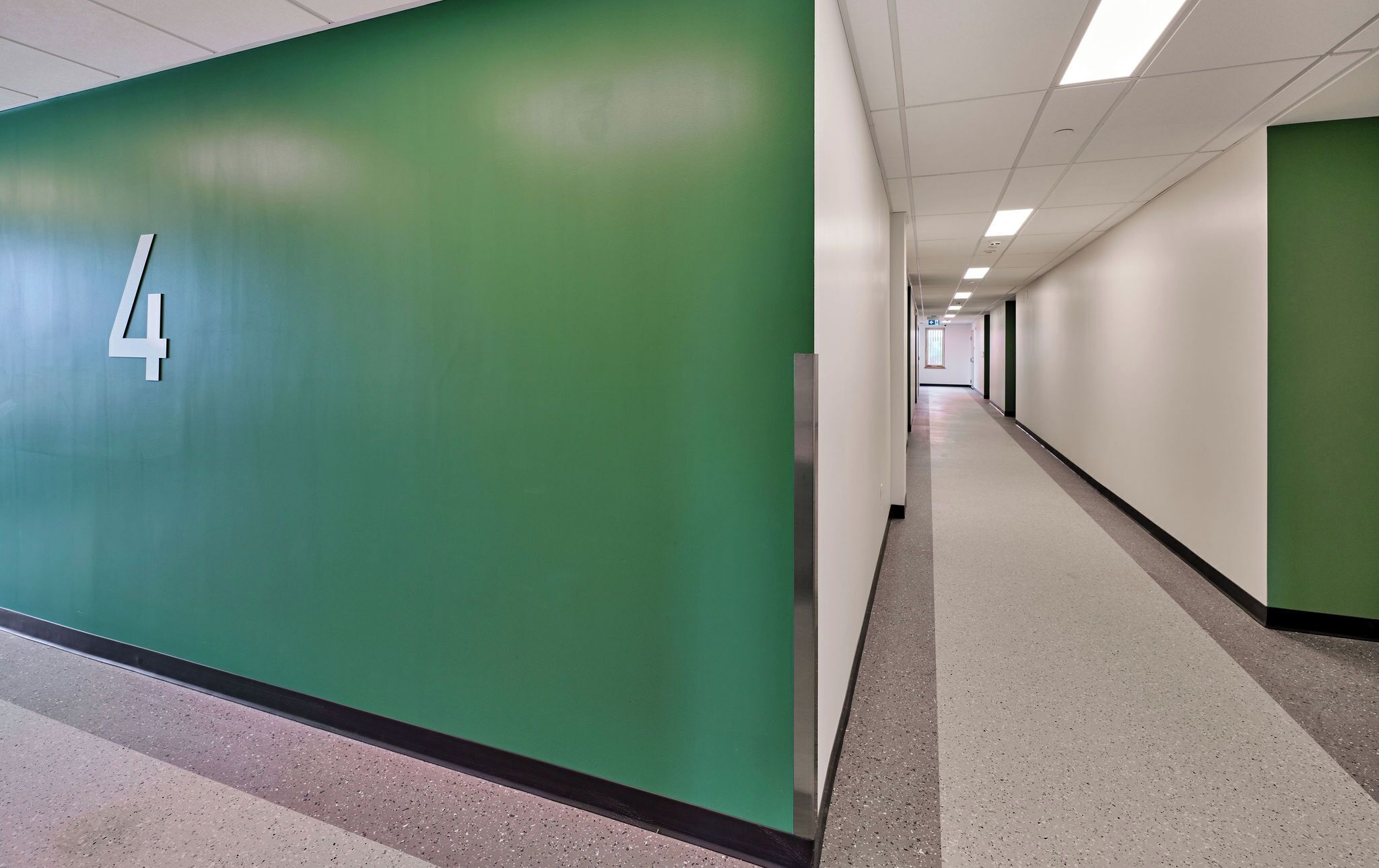Un couloir aux murs verts, un panneau indiquant le numéro « 4 », et un long corridor.