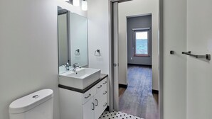 A modern bathroom with a white sink, mirror, and toilet.