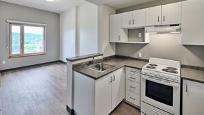 A modern kitchen with white cabinets, a stainless steel sink, and a built-in oven.