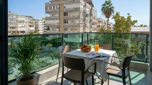 Ein Balkon mit Tisch, Stühlen, einer Topfpflanze und einer Obstschale.