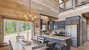 A wooden cabin interior with a dining area, kitchen, and a balcony. - Our Together Place 3 Bedroom Cabin (Sevierville)