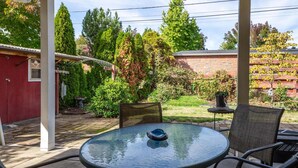 A patio with a round glass table, chairs, and a small grill. - Sunflower Studio - 7 Minutes To Uo & 4 Minutes To Downtown 1 Bedroom Studio (Eugene)