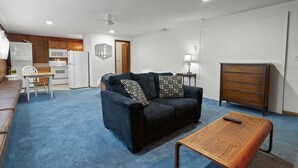 A compact living space with a kitchenette, a sofa, a wooden table, and a dresser. - Sunflower Studio - 7 Minutes To Uo & 4 Minutes To Downtown 1 Bedroom Studio (Eugene)