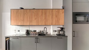 A modern kitchen with grey cabinets, a wooden upper cabinet, a built-in microwave, and a coffee maker. - Azzuro Living Sopot - Prime Location  (Sopot)
