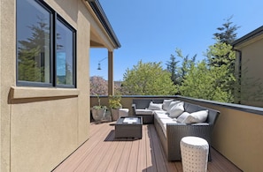 A balcony with a sofa, a table, and potted plants. - Birdhouse - Close To U Of O & Downtown 3 Bedroom Home (Eugene)