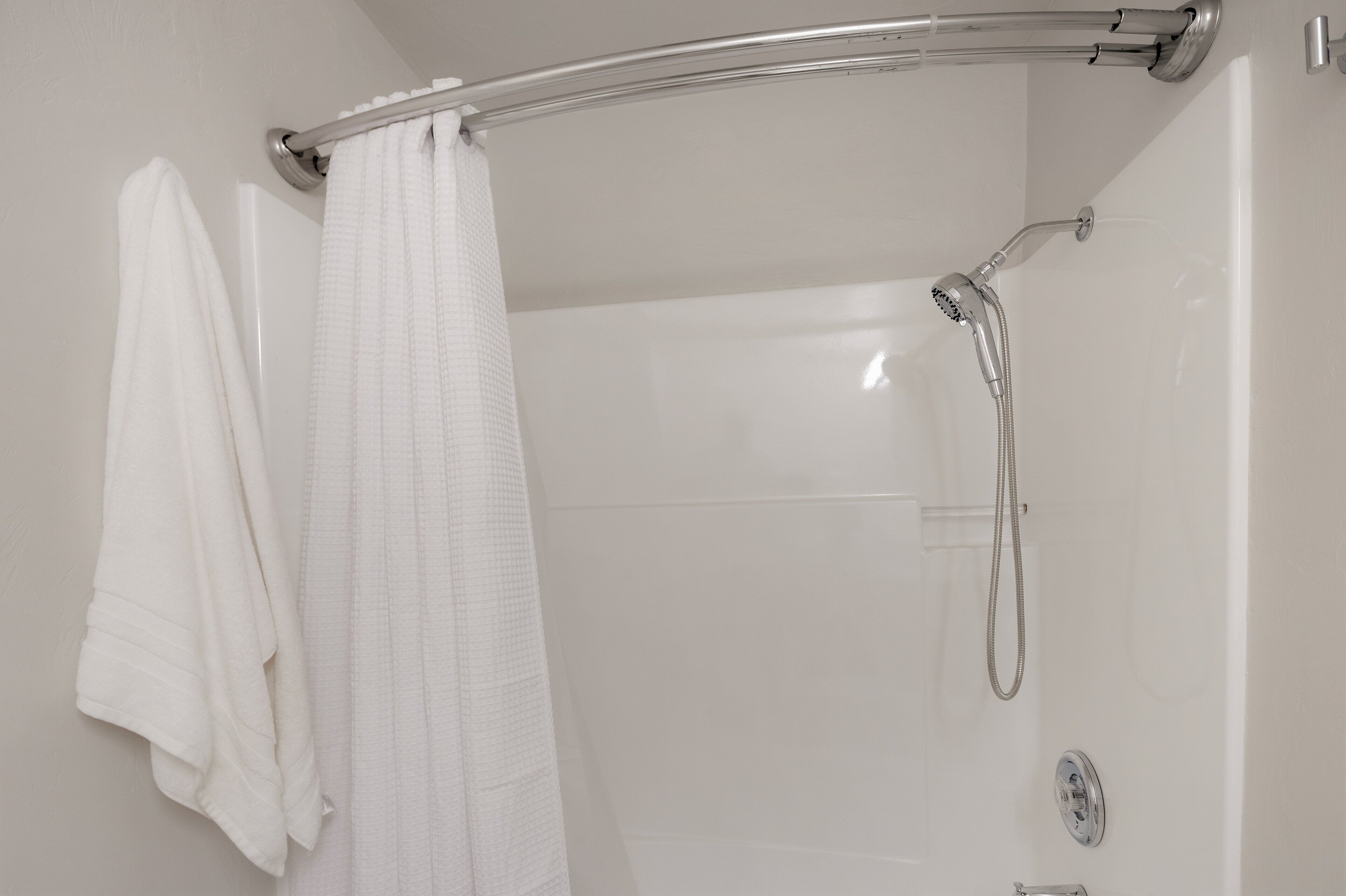A shower with a handheld showerhead and a glass door.