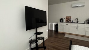 A modern bedroom with a flat-screen TV, a bed, a small seating area, and a kitchenette. - Super comfortable Studio in Margate. Host is amazing!!!! (Margate)