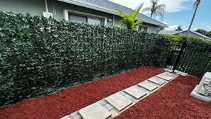 A landscaped garden with a hedge, red mulch, and stone pathway. - Super comfortable Studio in Margate. Host is amazing!!!! (Margate)