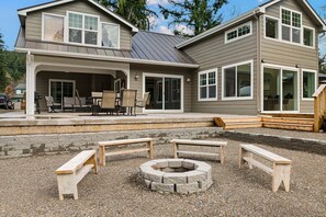 A two-story house with a covered patio, outdoor seating, and a fire pit.