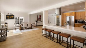 A modern kitchen with a central island, wooden cabinets, and stainless steel appliances. - River's Rest - Waterfront Views, Hot Tub, Grill & Fire Pit 3 Bedroom Home (Walterville)
