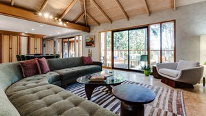 A spacious living area with a large sectional sofa, a glass coffee table, and a comfortable armchair. - Lumbermill Modern - Zen Sanctuary Near U Of O 3 Bedroom Home (Eugene)