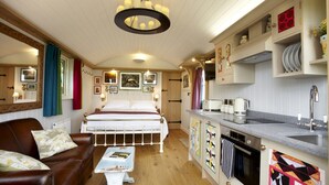 Una habitación compacta con cama, una mesita, un sofá, kitchenette y comedor.