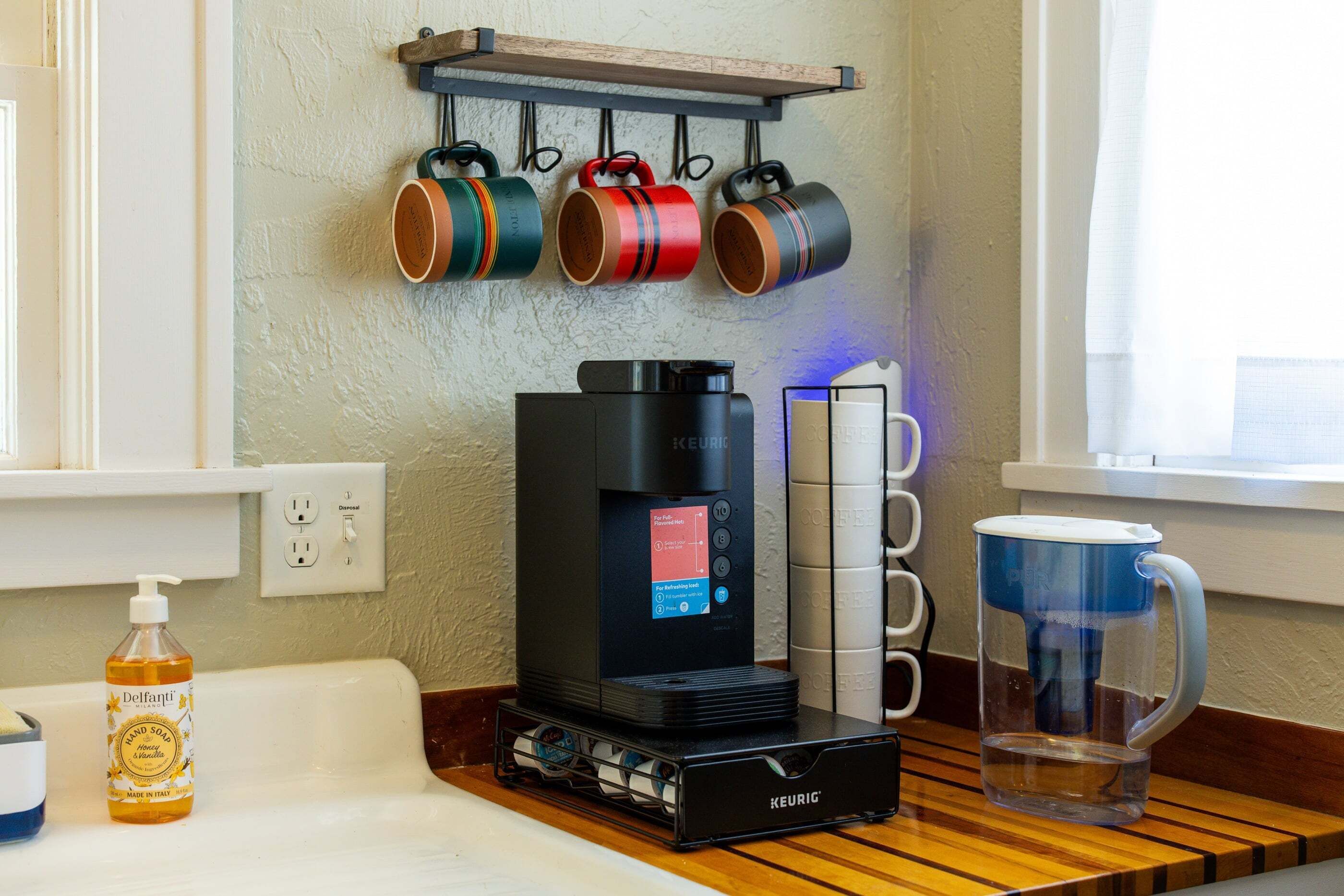 A coffee machine, a mug, and a bottle on a counter.