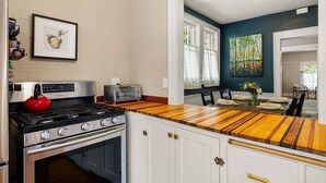 Una cocina con estufa a gas, un hervidor rojo y una encimera de madera.
