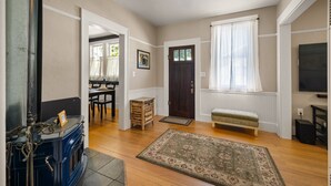 Una sala de estar con chimenea, un banco, un televisor y una puerta que da a otra habitación.