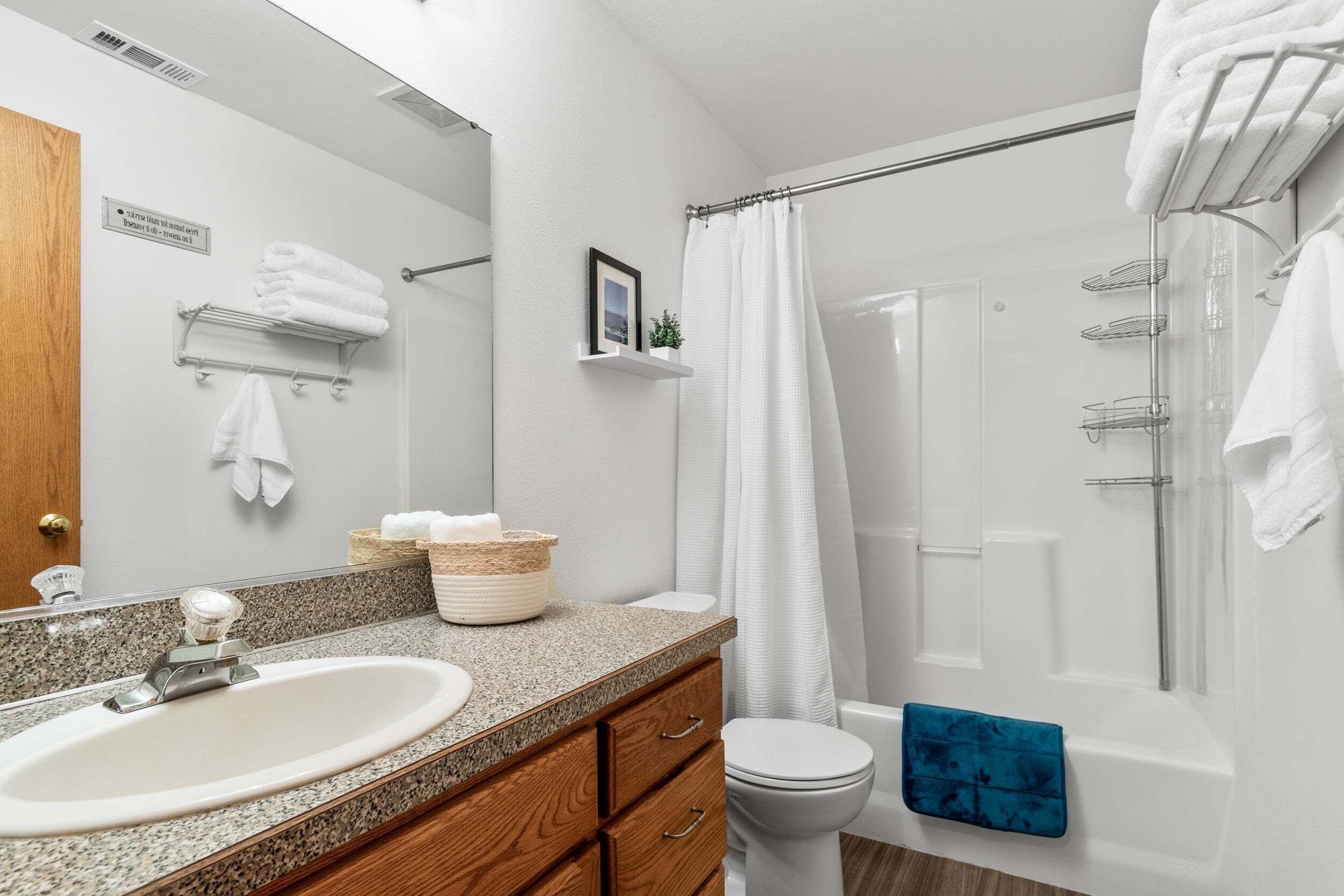 A bathroom with a sink, mirror, towel rack, shower, and toilet.