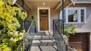 A house with a wooden front door, a covered porch, and a garage. - Orchard Luxe - Modern Home In Walking Distance To Uo 3 Bedroom Home (Eugene)