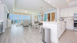 A spacious kitchen with a large island, white cabinetry, and a view to the outside. - Phoenix Gulf Towers 1005 4 Bedroom Condo (Orange Beach)
