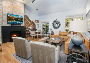 Una sala de estar moderna con chimenea, asientos cómodos, televisor y vistas al exterior.