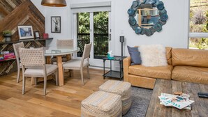A modern living room with a glass dining table, leather sofa, and a large mirror. - Coldstream #18 3 Bedroom Townhouse (Vail)