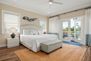 Una camera da letto con un letto, comodini, una ventola a soffitto e vista su un balcone.
