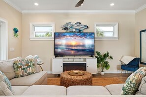 A living room with a fireplace, a flat-screen TV, and a comfortable seating area. - Coastal Livin' 3 Bedroom Home (Holmes Beach)