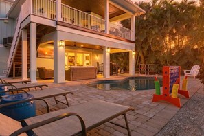 Une maison à deux étages avec une piscine, un espace extérieur aménagé pour s’asseoir et une terrasse couverte.