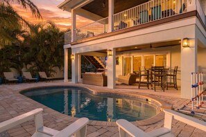 Un'area piscina con poltrone prendisole, una zona relax coperta e una scalinata che conduce a un livello superiore.
