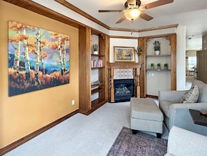 A living room with a fireplace, a ceiling fan, and a large painting on the wall. - Victorian Chateau Retreat 3 Bedroom Townhouse (Grand Junction)