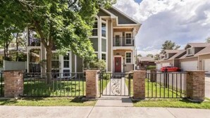 A two-story residential building with a gated entrance, a red door, and a garage. - Victorian Chateau Retreat 3 Bedroom Townhouse (Grand Junction)