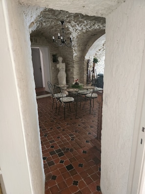 A dining area with a brick floor, white walls, and a stone archway. - CHARACTER VILLAGE HOUSE (Cabrières)