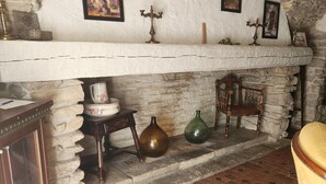 Ein rustikales Interieur mit Kamin aus Stein, einem Holzstuhl und einem Fliesenboden.