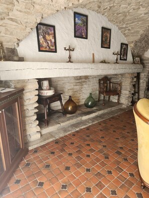 A rustic interior with a stone fireplace, a wooden chair, and a tiled floor. - CHARACTER VILLAGE HOUSE (Cabrières)