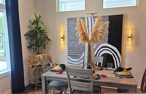 A dining area with a table set for four, a potted plant, and a decorative wall piece. - Wonderland 3bd Escape Near Downtown Houston (Houston)