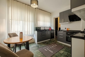 Eine moderne Küche mit Essbereich, ausgestattet mit einem runden Tisch, Stühlen, einer Kücheninsel und einer Mikrowelle.