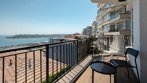 Een balkon met uitzicht op zee, een tafel en twee stoelen.