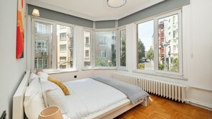 Een slaapkamer met een bed, een raam, een radiator en een lamp.