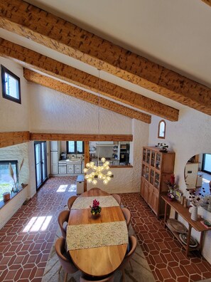 Ein Essbereich mit Holztisch, Stühlen, einer Kandelaber und einer Küche im Hintergrund.