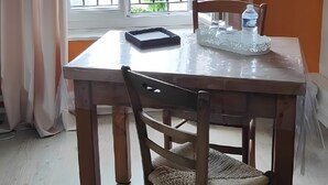 Una mesa de comedor con sillas, una ventana con cortinas y una botella de agua sobre una bandeja.
