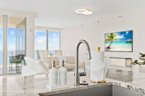 A modern kitchen with a sleek faucet, two soap dispensers, and a marble countertop. - Luxury 2BR 2.5BA Amrit Condo with ocean view (Riviera Beach)