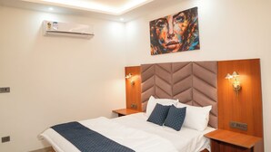 Un dormitorio moderno con cama, ventilador de techo, aire acondicionado instalado en la pared y una obra de arte.