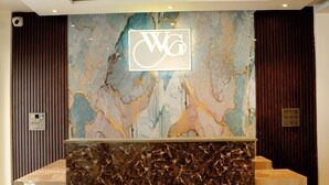 Un mostrador de recepción con pared de mármol y un logotipo.