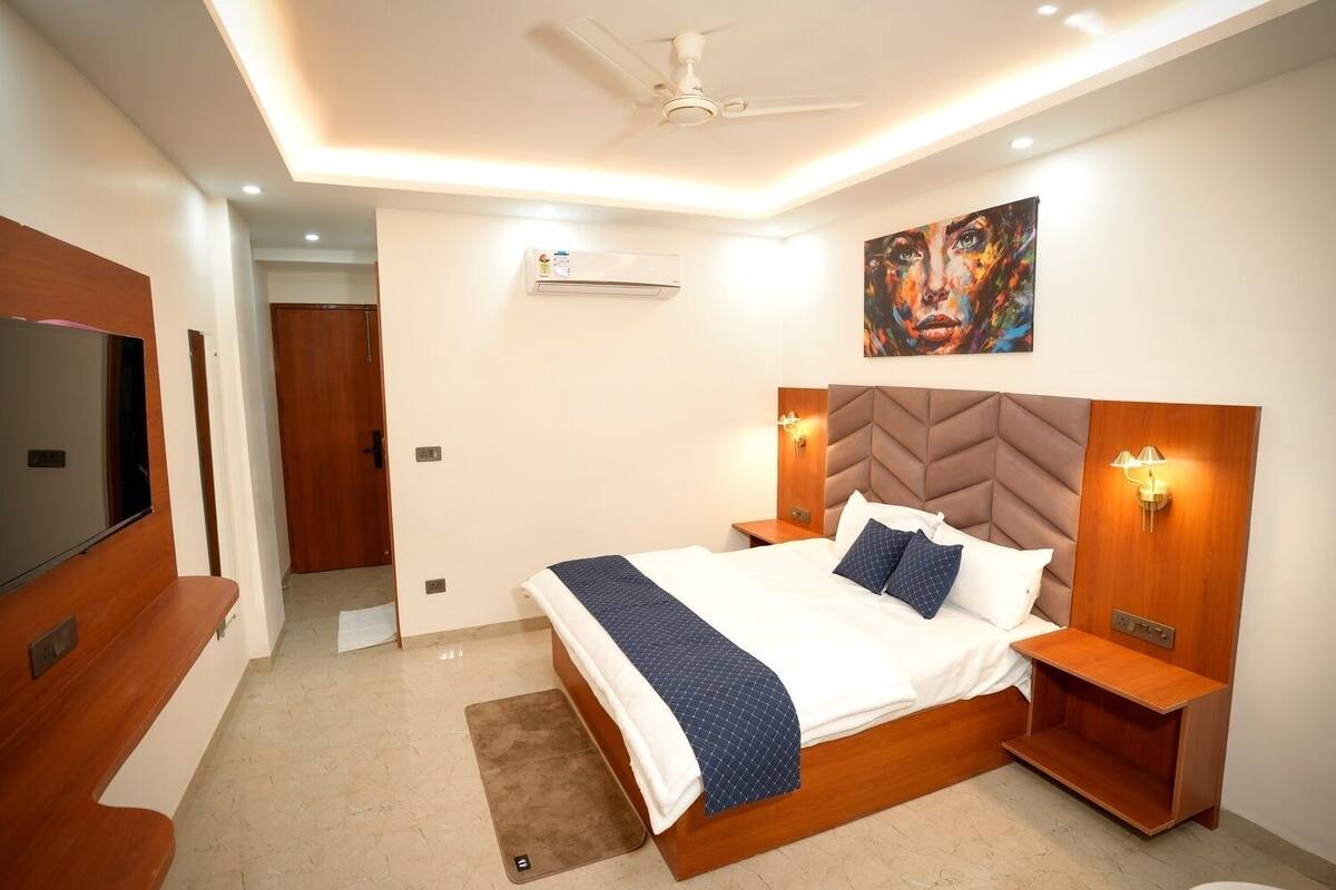 Une chambre d’hôtel moderne dotée d’un grand lit, d’un téléviseur à écran plat, d’un ventilateur de plafond et d’un tableau au mur.