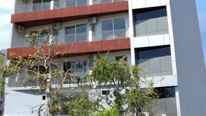 Un edificio de varios pisos con balcones, un cartel que dice 'GANGA VIEW CAFE' y un letrero que anuncia 'WHISPERING GANGA'.