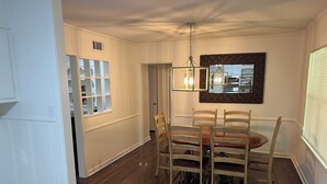 A dining area with a wooden table and chairs, a hanging light fixture, and a kitchen visible through an open door. - Marvelous 3-bedroom, newly renovated house with AC in charming Tyler (Tyler)
