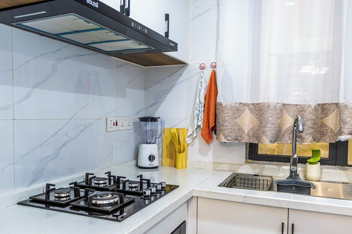 Une cuisine équipée d’une cuisinière à gaz, d’un mixeur et d’un évier.