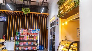 Ein Geschäft mit Regalen voller Colgate Zahnpasta, einem Schild für ein Café und einer Vitrine mit Gebäck.