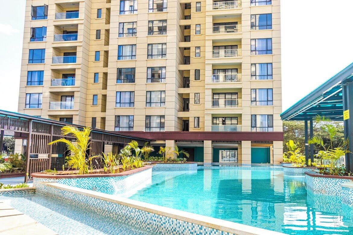 Um edifício alto com piscina na frente.