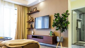 Ein Wohnzimmer mit Flachbildfernseher, Blumentopf, Sofa und einer Holz-Unterhaltungseinheit.
