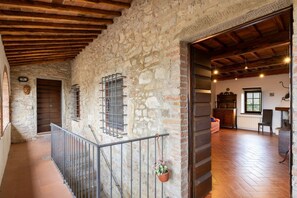 A stone-walled corridor with a wooden ceiling, a metal railing, and a hanging flower pot. - Charming 160 square meters apartment, perfect for six people, located on the first floor of a recently renovated medieval convent (no elevator).The property is located in Monti, a hamlet of Gaiole in Chianti: the area is extremely quiet and surrounded by (Monti)